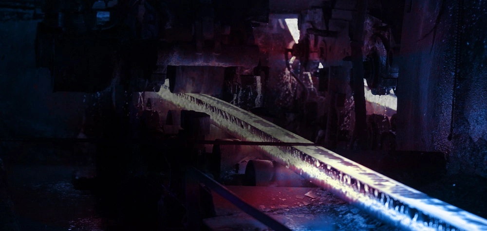 Heated ribbed steel bar moving through rolling equipment